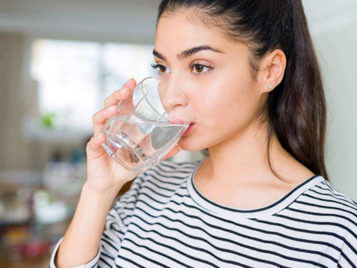 Ženska v črtasti majici pije vodo iz kozarca